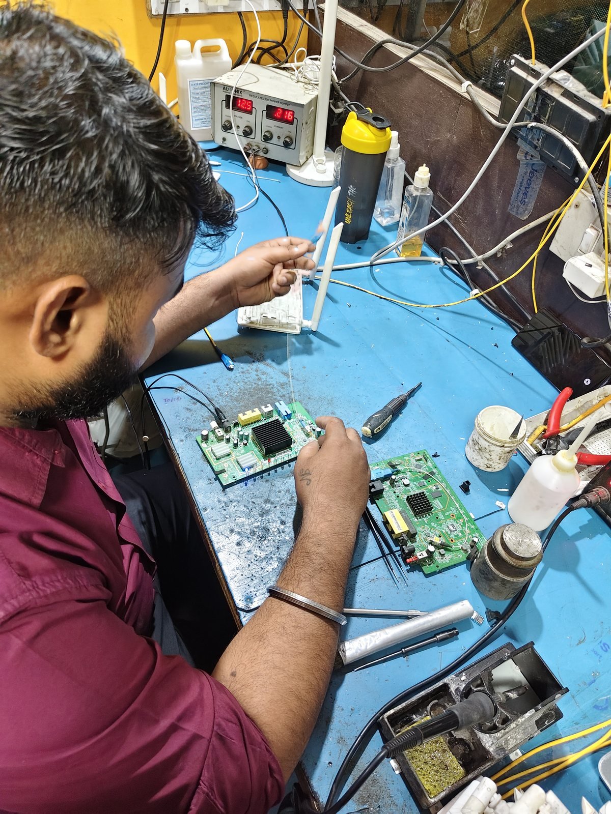 Technician inspecting a populated circuit board during repair