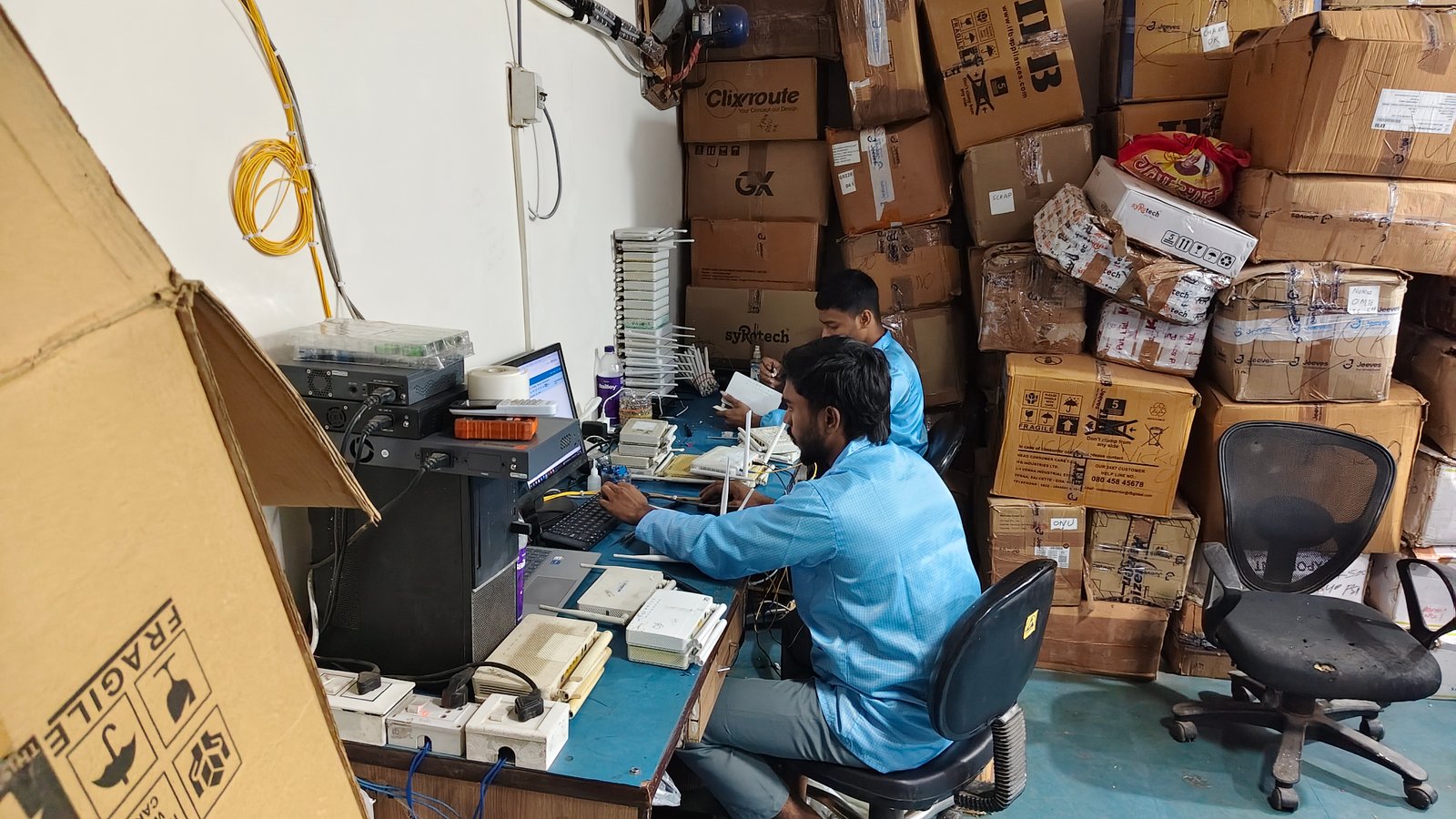 Technicians testing and configuring broadband devices at a repair station