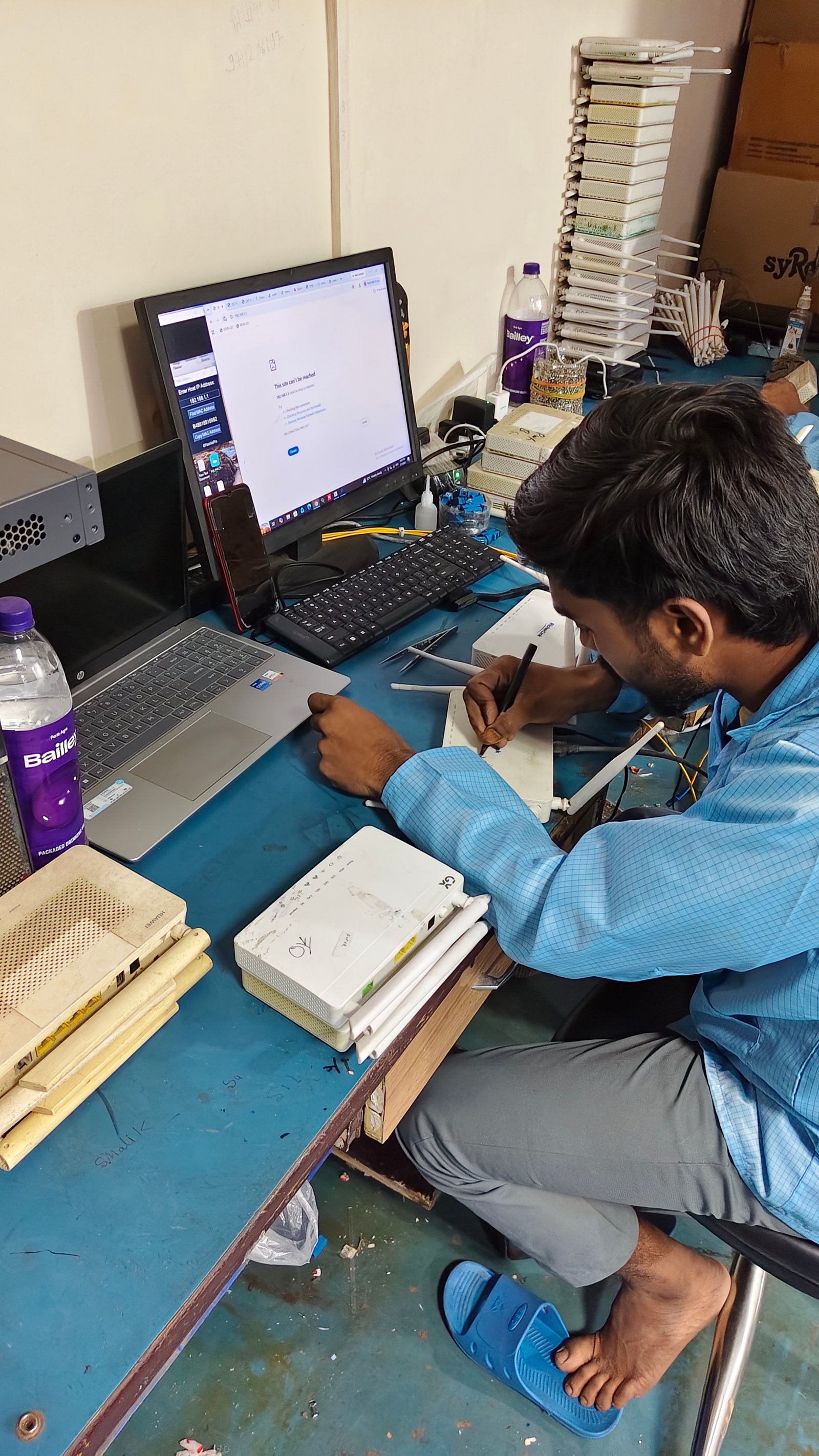 Technician configuring broadband equipment at a computer workbench